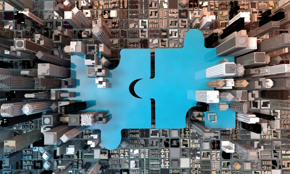 Overhead view of giant blue puzzle pieces joined together surrounded by buildings.