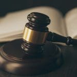 Closeup of gavel with law book in the background.