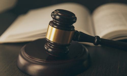 Closeup of gavel with law book in the background.