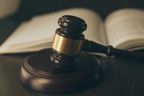 Closeup of gavel with law book in the background.