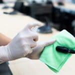 worker hand wearing gloves using disinfectant spray and cloth to clean microphone in conference room to prevent covid-19 or coronavirus infection. new normal and social distancing concept