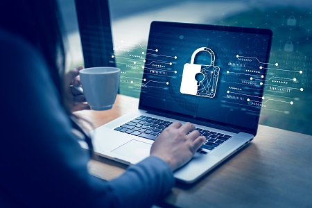 Person working on computer. The computer screen has a digital lock indicating security vulnerability.