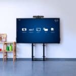 A tv next to a wooden shelf. The tv's screen has a mockup of a video conferencing screen.