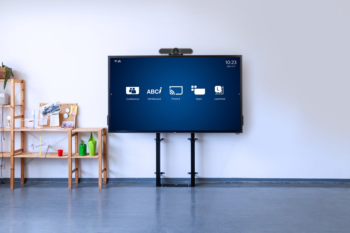 A tv next to a wooden shelf. The tv's screen has a mockup of a video conferencing screen.