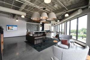 Large room with different seating arrangements and assorted coffee tables. White ceiling lamps hang overhead giving off a warm vibe.