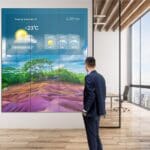 Mockup of Philips X-Line Videowall showcasing the weather while a person stands in front of it.