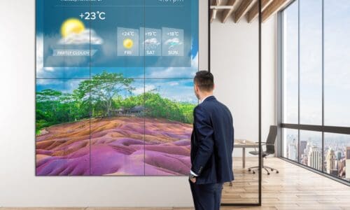 Mockup of Philips X-Line Videowall showcasing the weather while a person stands in front of it.