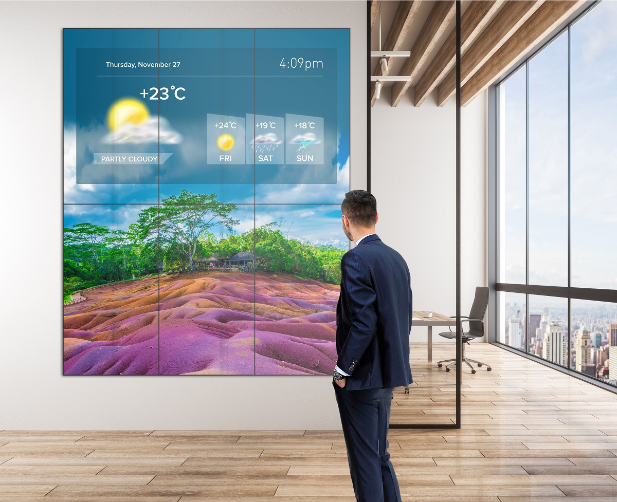 Mockup of Philips X-Line Videowall showcasing the weather while a person stands in front of it.