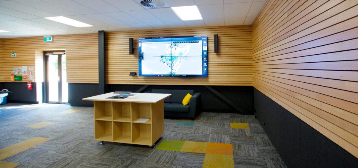 PowerCo's Network Operations Center. An empty room with a single table in the center. On the wall is a six-screen display with weather data on it