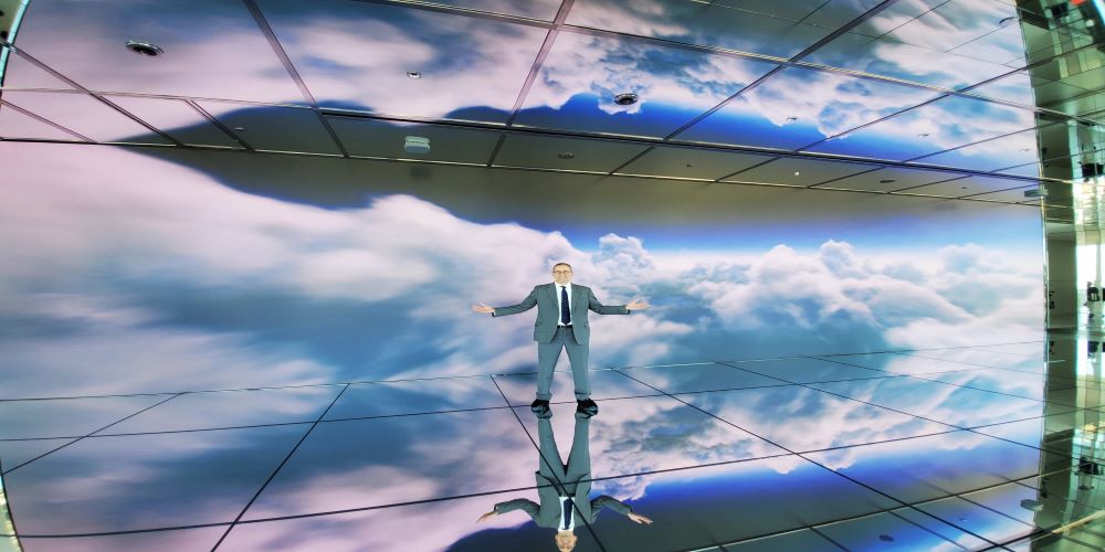 Person standing in front of a Samsung video wall displaying clouds.