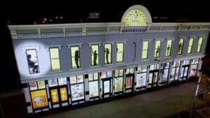 Building with projection display. Silhouettes of people appear on above windows. The lower level of windows have multicolor displays.