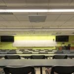 Empty classroom with tables and chairs. The BMA 360 is located on the ceiling of the classroom.