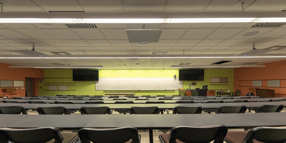 Empty classroom with tables and chairs. The BMA 360 is located on the ceiling of the classroom.