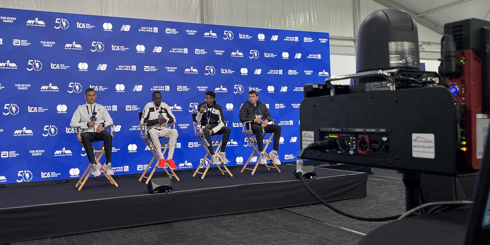 People sitting on podium for interview. Focus is on CP Communications Virtual Media Center CamSTREAM camera.