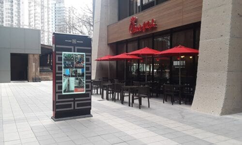 Digital Kiosk with Colony Square written on top of the screen. The kiosk stands next to a restaurant.
