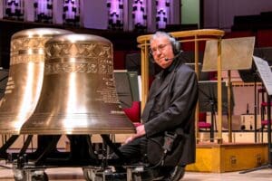 Person sitting with Riedel headphones next to a church bell