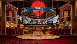 WynnBET Sports Bar. Above a table, a giant ring displaying content hangs around an LED basketball sphere.