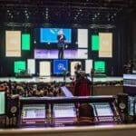 Person sitting with DiGiCo console in auditorium at Seacoast Church. In front, an audience is watching a speaker on stage.