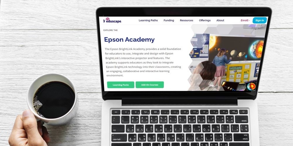 Mockup of Epson BrightLink Academy on a laptop. A person's hand holding a cup of coffee appears next to the laptop.