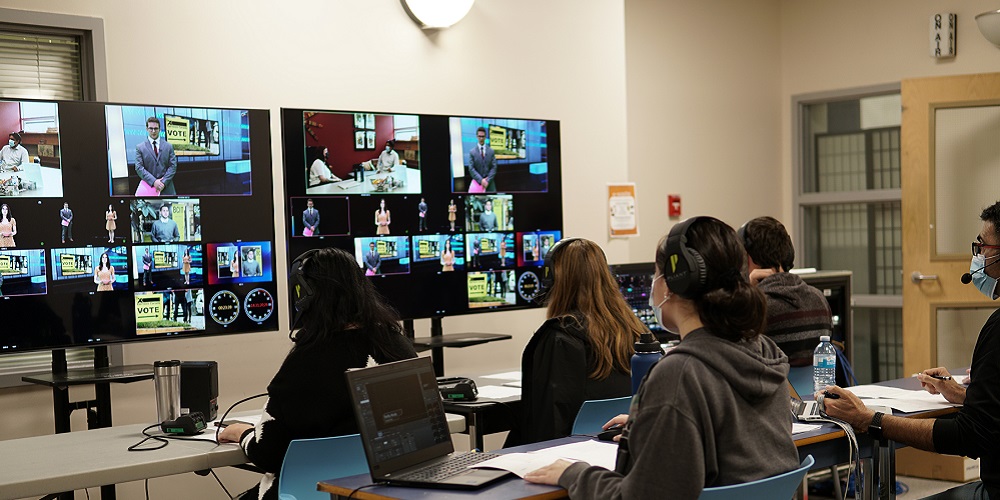 BCIT students wearing CrewCom headsets and observing a broadcast screen.