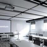 Empty conference room with projector screen that says "We design solutions, Sonitum."