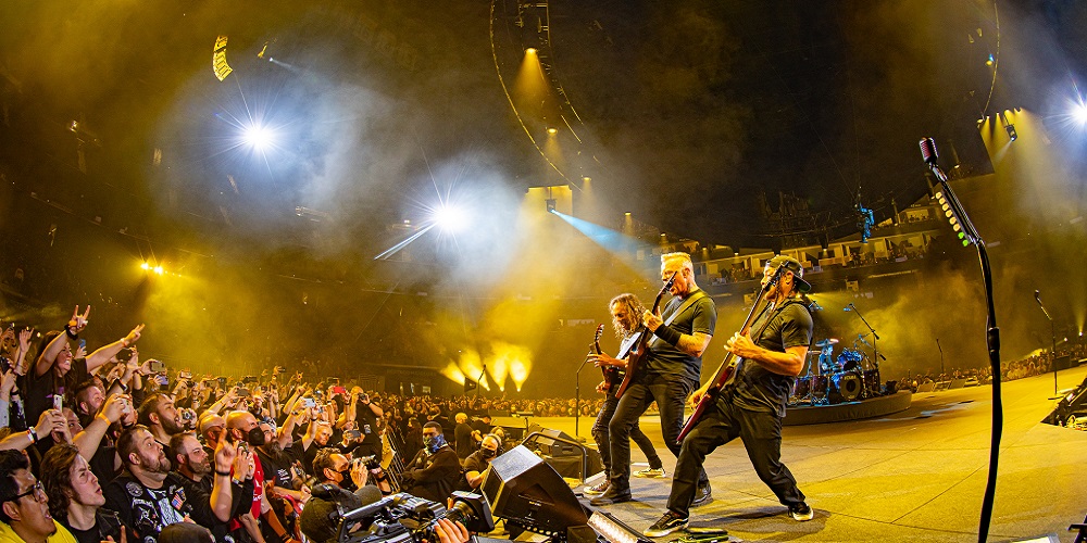 Metallica performing onstage while cameraperson holds Sony HDC camera to record them.