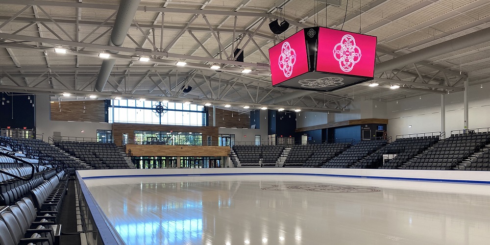 Bose speakers hanging from ceiling at Performance Center of Skating Club of Boston. A giant ED screen is also next to the speakers.