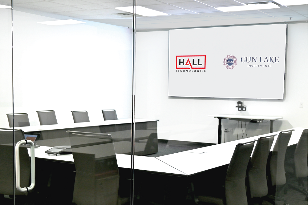 Projector screen in office room displaying logos of Hall Technologies and Gun Lake Investments.