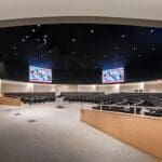 Four Planar videowalls mounted on curved ceiling of auditorium.