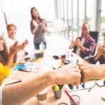 Coworkers fist bump in team meeting, happy colleagues clapping hands. Teamwork cooperation, company morale, company culture