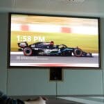 Person watching a Formula One car on a Crestron outfitted display.