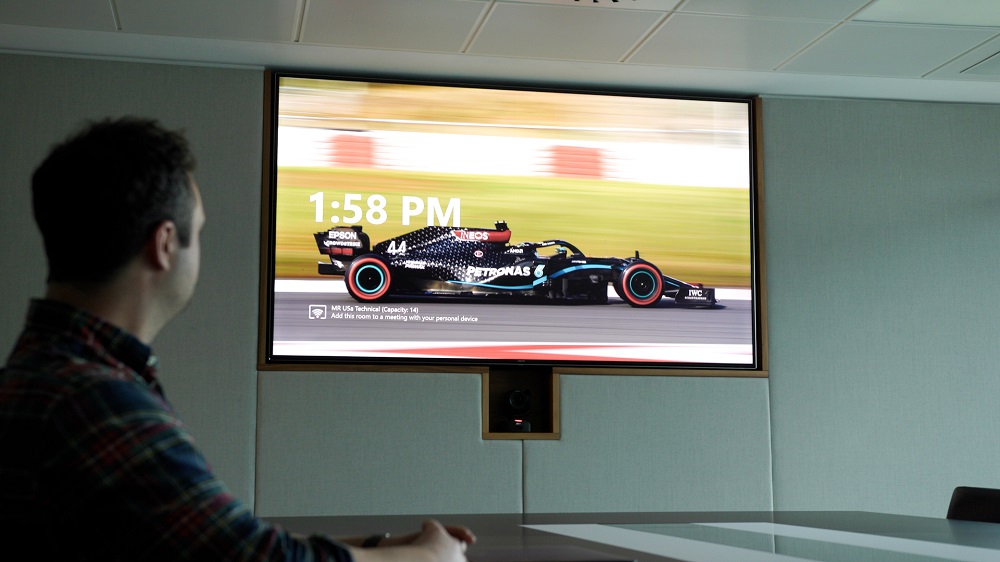 Person watching a Formula One car on a Crestron outfitted display.