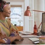 Employee wearing a Poly headset and attending a video meeting from home.