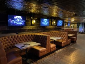 Restaurant booths in brown leather. On the sides are display monitors connected by Visionary PacketAV series and Q-SYS