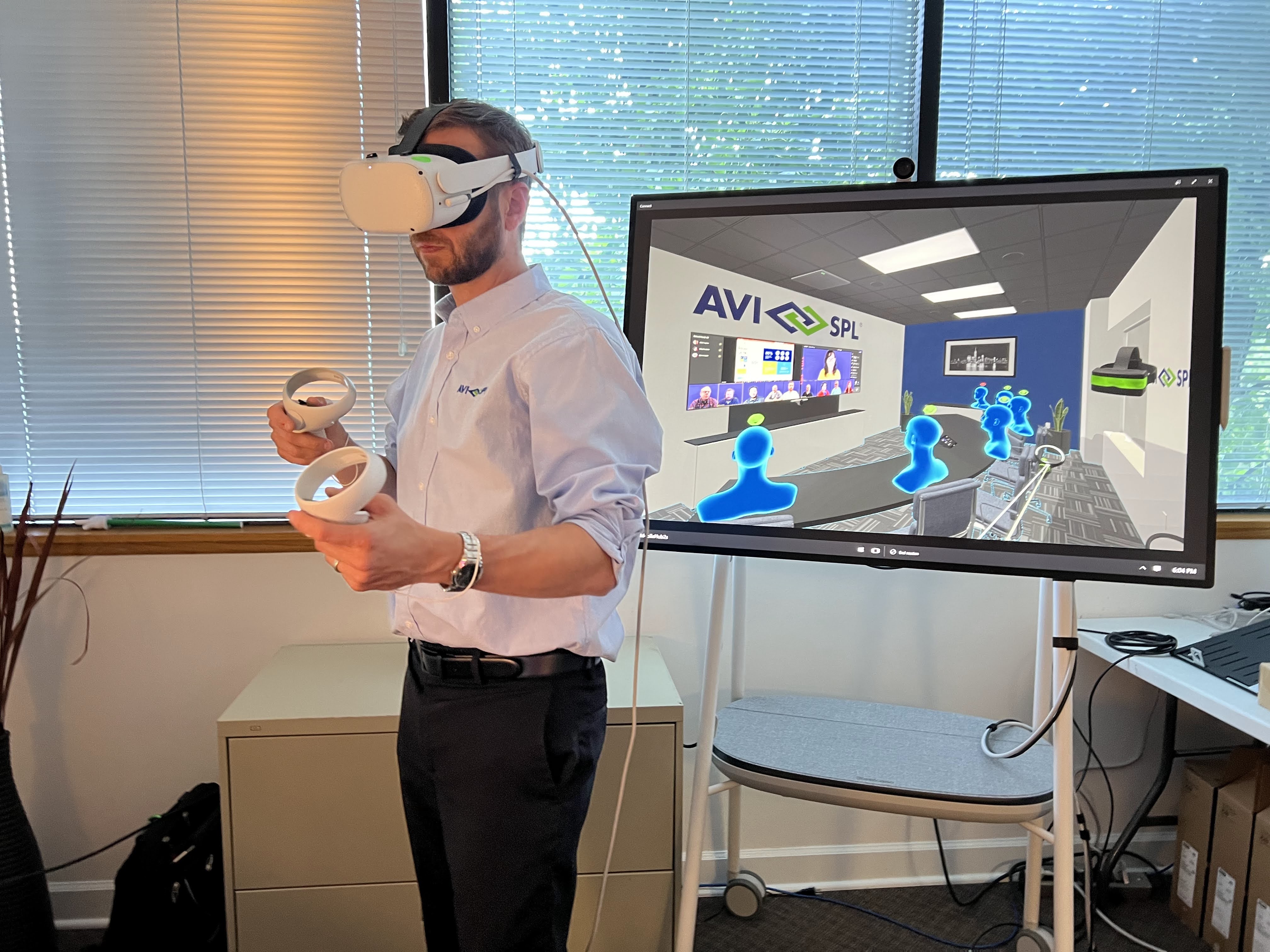 Person wearing VR headset. Behind is a display screen showing the room in VR.