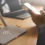 closeup of a wireless router and a person using smartphone on living room at home office