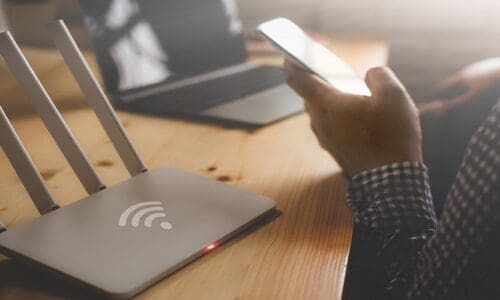 closeup of a wireless router and a person using smartphone on living room at home office