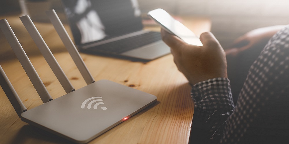 closeup of a wireless router and a person using smartphone on living room at home office