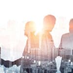 Double exposure shot of business people meeting on city office building in background depicting partnership success.