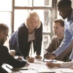 Older leader help diverse team in paperwork analysis at briefing, managing employees
