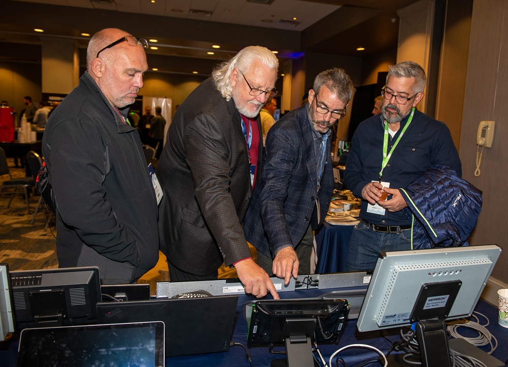 Attendees examining the E4 booth.