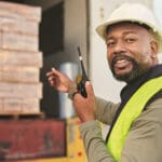 man unloading boxes out of truck with walkie-talkie in hand