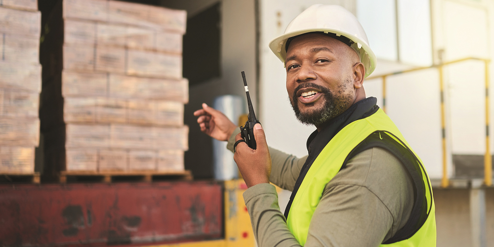 man unloading boxes out of truck with walkie-talkie in hand