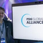 Cary Bran posing with screen that shows the logos of PSNI Global Alliance and Zoom.