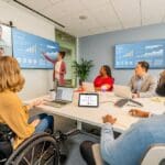 people sitting around large meeting room using Poly Studio Zoom Room bundle