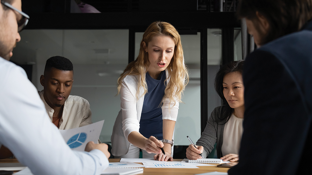 woman looking a budget on conference room table, teach research, team planning