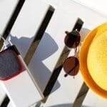 Music portable speaker is charged from the power bank via usb on a deck chair near the pool with beach accessories.
