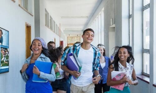 Students running down a campus hall and following signs on a Samsung digital display.