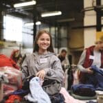 Volunteers sorting out donated clothes in community charity donation center, coronavirus concept.