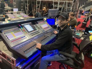 Person sitting with DiGiCo console and smiling at the camera.